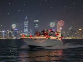A festive boat adorned with holiday decorations cruises through the city skyline as fireworks light up the night sky, creating a magical atmosphere for celebrations.