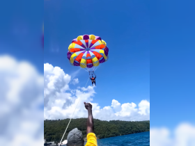 An exhilarating parasailing experience captures the thrill of adventure on the water, with stunning scenery in the background — perfect for those seeking excitement during their boat trip.