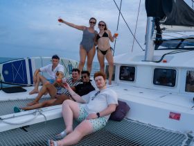 A lively group enjoys cocktails on a catamaran, celebrating together under the open sky — perfect for unforgettable summer adventures.