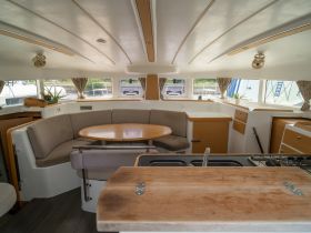 Interior view of a spacious boat cabin featuring comfortable seating and a dining area, perfect for relaxing and enjoying meals while on the water.