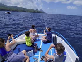A family enjoys a day on the water, pointing out sights while cruising on a boat — a perfect moment for adventure and exploration in a scenic location.