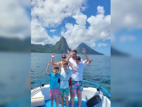 A joyful family poses on the deck of a boat with stunning island scenery in the background, capturing the essence of a fun-filled day on the water.