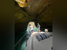 Two friends explore a stunning cave entrance while standing on the bow of their boat, showcasing the adventurous spirit of boating excursions.