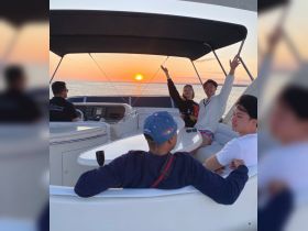 A joyful group of friends celebrates a beautiful sunset aboard a boat, creating unforgettable memories on the water.