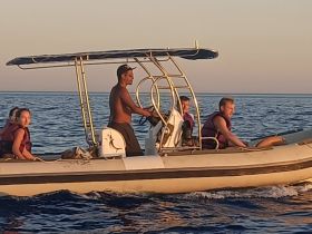 A group enjoys a thrilling boat ride at sunset, showcasing the excitement of water adventures with life jackets on.