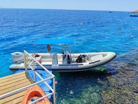A sleek speedboat is docked in crystal-clear waters, showcasing the vibrant blue hues of the sea — perfect for exploring coastal destinations.
