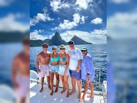 A cheerful group poses on the deck of a boat with stunning island scenery in the background, perfect for memorable family adventures and celebrations on the water.