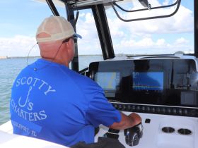 A captain navigates from the helm of a charter boat, showcasing the advanced console and navigation equipment — perfect for fishing charters in Gulfport, FL.