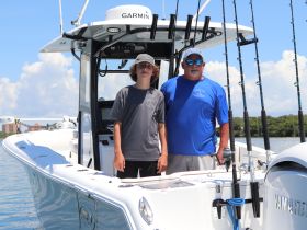 A young boy and an adult man pose together on a fishing boat, ready for a day of adventure on the water. Perfect for family fishing trips and bonding experiences.