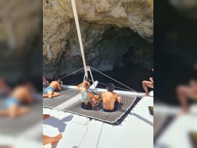 A group of friends relaxes on the netting of a catamaran, capturing the stunning cave entrance — a perfect moment of exploration and adventure on the water.