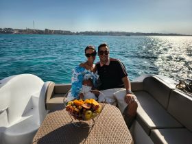 A couple enjoys a sunny day on a boat, surrounded by fresh fruit, perfect for romantic outings or celebrations on the water.