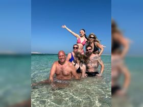 A joyful group of friends enjoys a fun day at the beach, celebrating and swimming in crystal-clear waters — perfect for memorable summer outings.