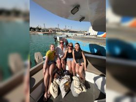 A cheerful group of friends enjoys their time on a boat, capturing the essence of a fun day out on the water under the sun.