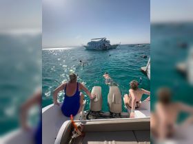 A group enjoys snorkeling in crystal-clear waters, with a boat anchored nearby, creating the perfect setting for aquatic adventures.