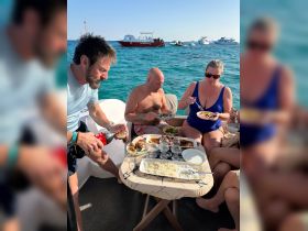 A lively group enjoys a delicious meal on a boat, showcasing the perfect blend of dining and socializing while surrounded by beautiful waters.