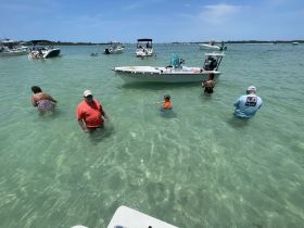 A family enjoys a fun day in the shallow waters, surrounded by boats, perfect for a summer outing at the beach.