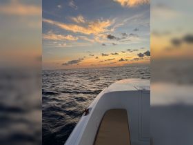 A serene view of a boat's hull against a stunning sunset over the ocean, perfect for capturing the tranquility of a boating experience.