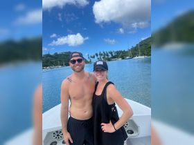 A happy couple poses on the deck of a boat with stunning tropical scenery in the background, perfect for romantic getaways or memorable adventures on the water.
