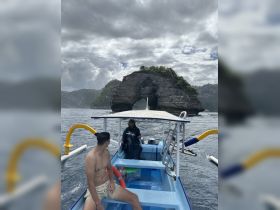 Two friends enjoy a boat ride near a stunning rock formation, capturing the essence of adventure and exploration in beautiful waters.
