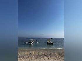 Two traditional boats anchored near a sandy beach under a clear blue sky, perfect for exploring coastal waters.