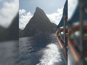 A scenic view of a boat navigating through the ocean with a stunning island backdrop, perfect for adventure seekers exploring beautiful landscapes.