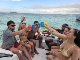 A lively group of friends cheers with colorful cups aboard a boat, enjoying a fun day on the water with food and drinks — perfect for celebrations and memorable outings.