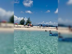 A vibrant beach scene with groups enjoying the sun and swimming in clear waters, perfect for a relaxing sandbar stop.