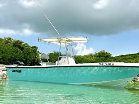 A stunning center console boat anchored in crystal-clear waters, showcasing its sleek design and vibrant colors — perfect for fishing or leisure outings.