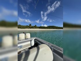 A scenic view from the deck of a boat, showcasing clear turquoise waters and a lush shoreline, perfect for a day of relaxation and exploration.