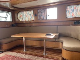 Cozy interior of a boat featuring a comfortable seating area and dining table, perfect for relaxing and enjoying meals while on the water.
