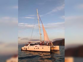 A lively group enjoys a sunset sail on a catamaran, capturing the essence of adventure and celebration on the water.