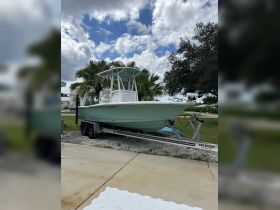 A sleek boat is docked, showcasing its design against a backdrop of palm trees and a cloudy sky — perfect for fishing or leisure outings.