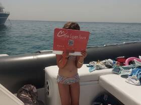 A child holds a sign for 'More Egypt Tours' on a boat, showcasing a fun day on the water. The vibrant atmosphere captures the essence of family-friendly boating adventures.