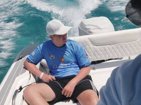 A young boy relaxes on the deck of a boat, enjoying a sunny day on the water — perfect for family outings and aquatic adventures.
