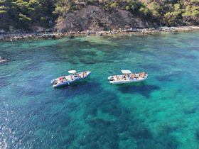 A lively group enjoys a day on the water aboard two boats, surrounded by stunning clear waters — perfect for summer adventures and social gatherings.