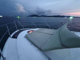 A serene view from the front of a yacht at dusk, showcasing the calm waters and distant lights, perfect for evening cruises.