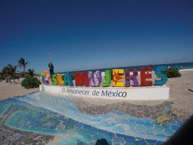 A vibrant photo of a tourist posing with the colorful Isla Mujeres sign, capturing the essence of this beautiful Mexican island destination.