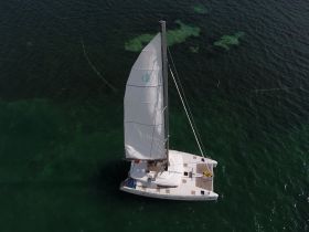 Aerial view of a sleek catamaran sailing through clear turquoise waters, showcasing its elegant design and perfect for adventurous sea trips.