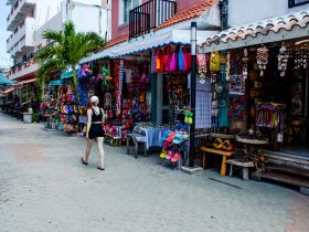 A woman walks through a vibrant market filled with colorful crafts and souvenirs, showcasing the local culture and shopping experience.
