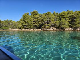 A stunning view of crystal-clear turquoise waters and lush greenery along the coastline, perfect for a serene boating experience.