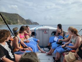 A lively group of friends enjoys a boat ride, soaking up the sun and the beautiful coastal scenery — perfect for a day of adventure on the water.