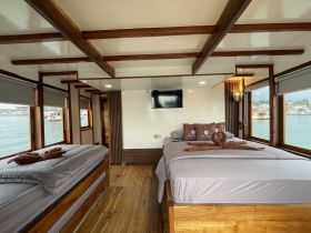 Interior view of a cozy boat cabin featuring comfortable sleeping arrangements and large windows offering scenic views of the water — perfect for relaxing getaways.