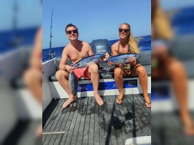 A couple proudly displays their catch while fishing on a boat, showcasing the thrill of a successful day on the water.