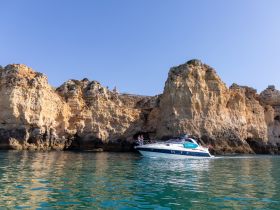 A scenic view of a boat navigating along a stunning coastline, showcasing the beautiful cliffs and clear waters — perfect for exploring coastal landscapes.