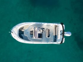 Aerial view of a sleek speedboat resting on clear turquoise waters, showcasing its elegant design and spacious deck — perfect for a day of adventure on the water.