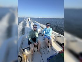 Two friends enjoy a sunny day on the water, relaxing on a boat — perfect for a fun outing or adventure with friends.