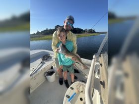 A joyful father and son proudly display their catch while fishing on a boat, capturing a memorable outdoor adventure together.