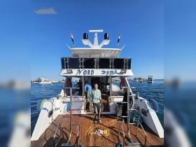 A crew member stands on the deck of the Nord yacht, showcasing its sleek design and inviting atmosphere at the dock — perfect for luxury boating experiences.
