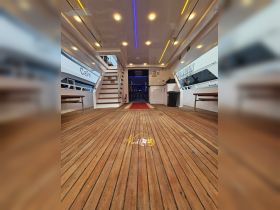 Interior view of a spacious boat cabin featuring polished wooden flooring and modern lighting, perfect for comfortable gatherings and relaxation on the water.