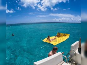 A fun day on the water with friends enjoying a floating mat in crystal-clear turquoise waters — perfect for sunbathing and relaxation.